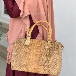 Könnte beinhalten: Eine weiße Keramik-Tasse mit schwarzem Henkel und dem Text "But first, coffee" in schwarzer, handschriftlicher Schrift. Die Tasse steht auf einer weißen Oberfläche.