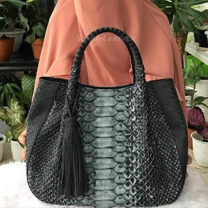 May include: A white ceramic mug with a black handle and the text "But First, Coffee" in a bold, black font. The mug is set against a neutral background, highlighting its simple design.