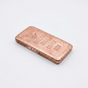 Peut inclure: Barre de cuivre avec le texte "ORALYSE 200G COPPER 999" et un logo. La barre est rectangulaire et a un aspect légèrement usé. La barre pèse 200 grammes.