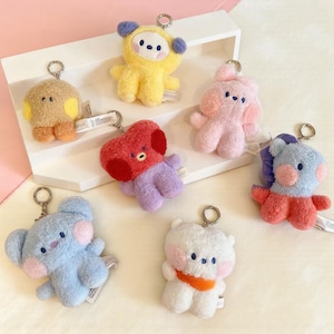 May include: A collection of plush keychains in various colors and designs. The keychains feature cartoon-like characters in yellow, pink, red, purple, blue, brown, and white. Each keychain has a metal ring for attachment.