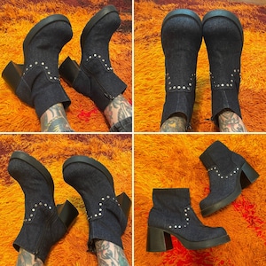 May include: A pair of denim ankle boots with silver studs. The boots have a chunky heel and a pointed toe. The boots are shown on a model wearing them on both feet.