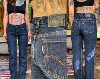 May include: Dark wash denim jeans with a straight leg fit. The jeans have a classic five-pocket design with orange stitching and a frayed hem. A leather patch with the text "silverlab" is visible on the back waistband.