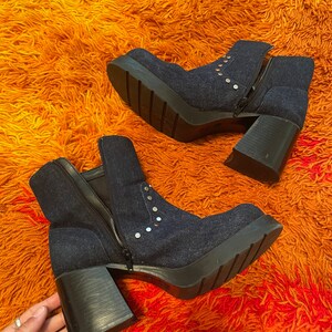 May include: A pair of dark blue denim ankle boots with silver studs and chunky heels. The boots have a zipper on the side and a platform sole.