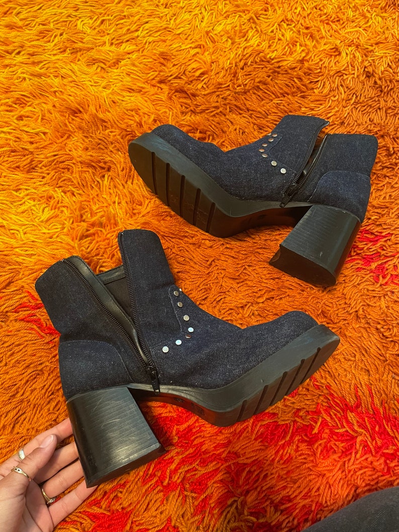 May include: A pair of dark blue denim ankle boots with silver studs and chunky heels. The boots have a zipper on the side and a platform sole.