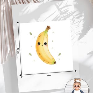 Könnte beinhalten: Eine quadratische weiße Karte mit einer gelben Bananenillustration, die ein lächelndes Gesicht, schwarze Augen und rosa Wangen hat. Die Karte misst 13 cm in der Höhe und 4 cm in der Breite. Kleine grüne Blätter und Punkte umgeben die Banane.