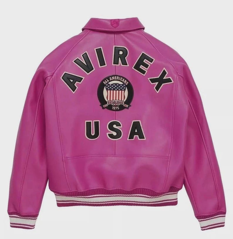 Pode incluir: Jaqueta de couro f&uacute;csia vibrante com a palavra "AVIREX" em letras pretas nos ombros. Abaixo, a palavra "USA" est&aacute; em exibi&ccedil;&atilde;o. Um patch circular com as palavras "ALL AMERICANS ESTABLISHED 1975" est&aacute; centralizado.