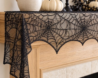 May include: A black lace table runner featuring an intricate spider web pattern. The fabric is semi-sheer with a scalloped edge, designed to drape over the side of a wooden mantelpiece, showcasing a detailed mesh construction throughout.