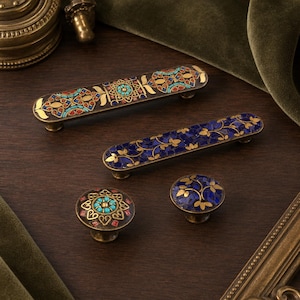 May include: Two elongated rectangular drawer pulls and two round cabinet knobs featuring intricate mosaic inlays. One pull and one knob display a geometric pattern with turquoise and red accents, while the others feature a blue floral leaf design.