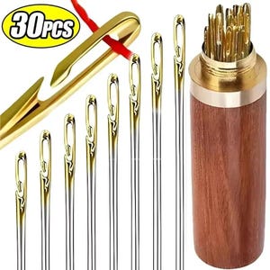 May include: A selection of sewing needles with gold-coloured eyes and silver shafts. The image includes a wooden needle holder with a brass top and a large gold needle with red thread. The text "30pcs" is in a yellow oval.