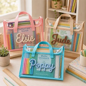 Peut inclure: Trois sacs rectangulaires en maille transparente avec des poignées en tissu, chacun personnalisé avec un nom en lettres de laine en relief. Le sac rose porte le nom 'Elsie', le beige 'Jude' et le bleu 'Poppy'. Chaque sac contient des livres, des crayons de couleur et une règle.