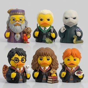 Könnte beinhalten: Eine Sammlung von sechs gelben Quietscheentchen, die als Charaktere aus einer Fantasy-Serie verkleidet sind. Die Figuren umfassen einen Zauberer mit Bart, einen Schüler mit blondem Haar, einen blassen Bösewicht, einen Jungen mit Brille, ein Mädchen mit braunem Haar und einen Jungen mit rotem Haar.