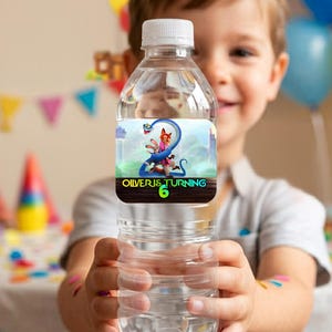 Close up of a hand holding a clear water bottle wrapped in a custom printed Zootopia 2 birthday label. The personalized wrapper reads Happy Birthday Caleb with vibrant colors and high-quality character graphics, demonstrating the final assembled DIY party favor.