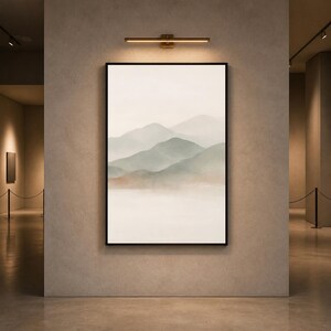 May include: A vertical rectangular wall art piece in a thin black frame featuring a watercolor-style landscape painting of layered mountain ranges in muted sage green and soft brown tones against a pale cream background.