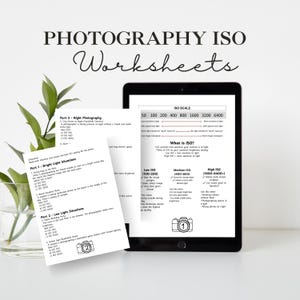 May include: A digital tablet displays a photography ISO worksheet, with text and diagrams explaining ISO settings. The title "PHOTOGRAPHY ISO Worksheets" is at the top. A printed worksheet is next to the tablet, with green leaves in a vase.