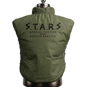 May include: Olive green vest with the text "S.T.A.R.S. SPECIAL TACTICS AND RESCUE SERVICE" printed in black. The vest has a high collar and a quilted appearance. The vest is displayed on a mannequin.