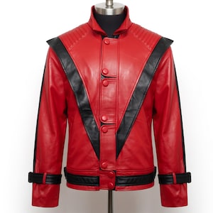 May include: A red leather jacket with black accents, featuring a stand-up collar, shoulder epaulets, and a button-up front. The jacket has black stripes down the sleeves and around the cuffs. The jacket is displayed on a mannequin.