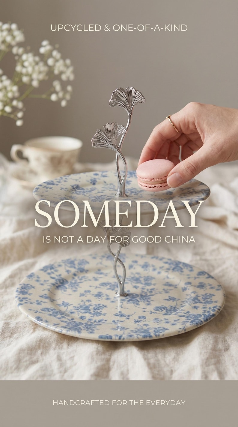 May include: A two-tiered serving stand with a floral design in blue and white. The stand has a silver metal handle with a leaf design. The text "SOMEDAY IS NOT A DAY FOR GOOD CHINA" is visible. The text "UPCYCLED & ONE-OF-A-KIND" and "HANDCRAFTED FOR THE EVERYDAY" are also visible.