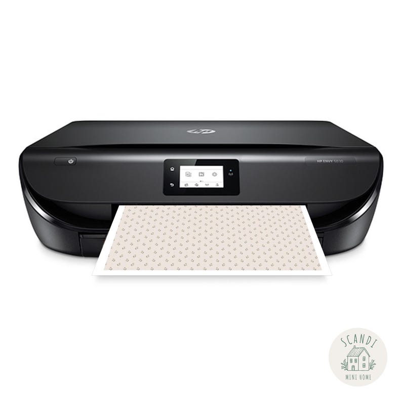 Op de afbeelding: Zwarte HP ENVY 5055 all-in-one printer met een klein LCD-scherm. Een bedrukt vel met een herhalend bloemenpatroon komt uit de printer. De printer staat op een witte achtergrond.