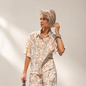 Puede incluir: Conjunto de camisa y pantal&oacute;n corto a juego con estampado floral beige. La camisa de manga corta tiene un bolsillo en el pecho. Los pantalones cortos son de cintura alta. El conjunto es de tejido ligero.