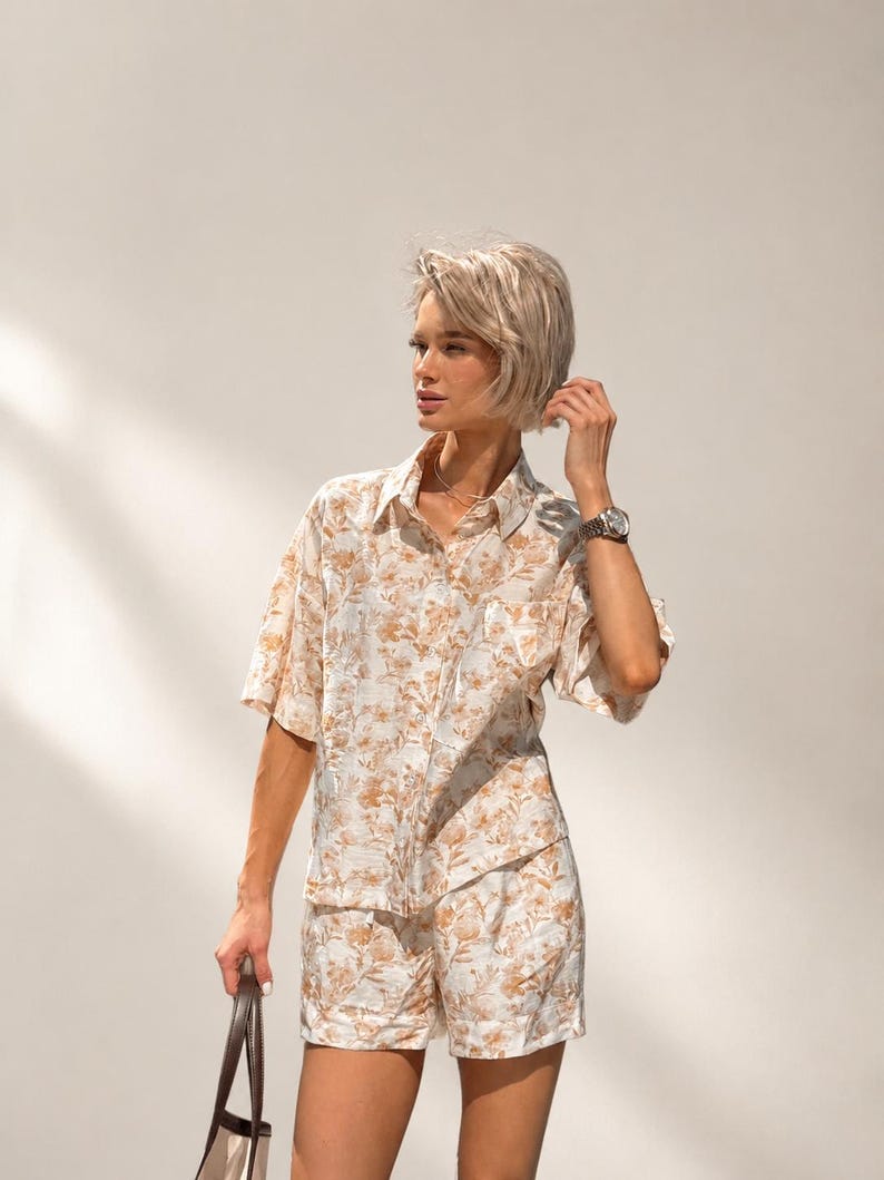 Puede incluir: Conjunto de camisa y pantal&oacute;n corto a juego con estampado floral beige. La camisa de manga corta tiene un bolsillo en el pecho. Los pantalones cortos son de cintura alta. El conjunto es de tejido ligero.