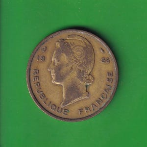 Könnte beinhalten: Eine bronzefarbene französische Münze von 1956 mit dem Profil einer Frau mit Lorbeerkranz. Die Münze trägt die Inschrift "REPUBLIQUE FRANCAISE" am Rand.