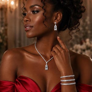 May include: A silver-toned jewelry set featuring a necklace with a central emerald-cut stone pendant, matching drop earrings with round and emerald-cut stones, and three stacked tennis bracelets with round and emerald-cut stones.