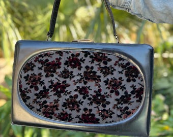 Bolso Supreme vintage de los años 60, de piel negra, con asa superior y panel floral de terciopelo. Estilo de mediados de siglo.