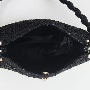 May include: Black beaded handbag with a braided handle. The interior is black satin. The bag has a gold-colored clasp and hardware. The bag is open, showing the interior.