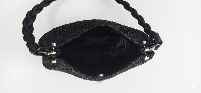 May include: Black beaded handbag with a braided handle. The interior is black satin. The bag has a gold-colored clasp and hardware. The bag is open, showing the interior.