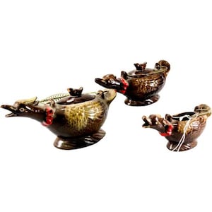Peut inclure: Un ensemble de trois récipients en céramique brune en forme de canard avec des finitions brillantes, des accents rouges au cou, des détails d'ailes texturés et des anses en fil métallique. Chaque pièce est sculptée avec un bec ouvert.