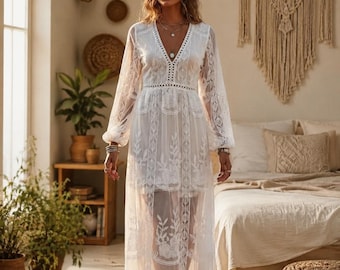 Puede incluir: Un vestido blanco largo hasta el suelo con mangas largas transparentes y un escote en V profundo. La prenda está confeccionada en tela de encaje intrincada con bordados florales detallados, una cintura entallada y una falda superpuesta con acabado semitransparente.