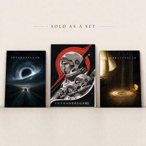 May include: Set of three "Interstellar" themed art prints. The prints feature space-themed illustrations, including a black hole, astronauts, and a light-filled room. The prints are displayed on a neutral background.