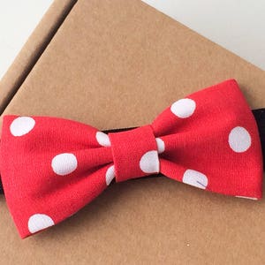 May include: Red bow tie with white polka dots on a black elastic headband.