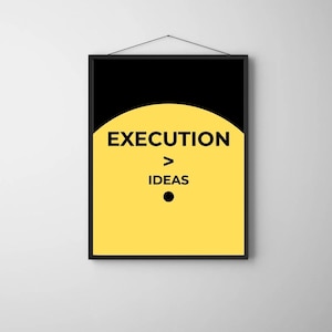 May include: A framed poster with a black border and a white wall background. The poster features the text "EXECUTION > IDEAS" in black font on a yellow background, with a black semi-circle at the top and a black dot below the text.