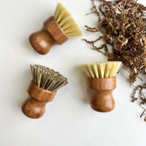 Puede incluir: Un juego de tres tazas de cerámica con un acabado mate moteado. Las tazas son en tonos crema, gris claro y gris oscuro. Cada taza tiene un diseño simple y minimalista y un asa redondeada.