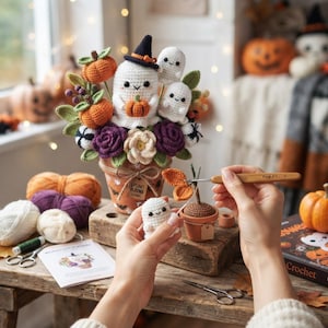Può includere: Una composizione all'uncinetto in un vaso di terracotta con un fantasma bianco con cappello nero, due fantasmi più piccoli, zucche arancioni e fiori viola. Un piccolo fantasma viene assemblato con un uncinetto dal manico in legno.