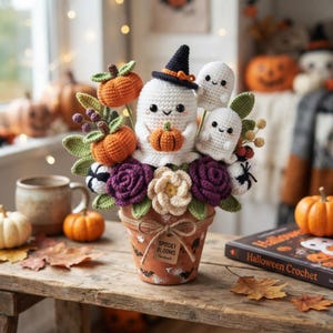Può includere: Una composizione all'uncinetto in un vaso di terracotta con un fantasma bianco che indossa un cappello da strega nero, due fantasmi più piccoli, zucche arancioni, fiori viola e crema e foglie verdi. Un'etichetta sul vaso riporta Spooky Blooms Handmade.