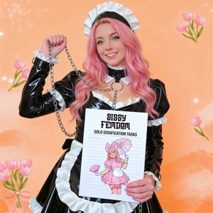 Könnte beinhalten: Eine Person mit rosa Haaren in einem schwarz-weißen Dienstmädchen-Outfit hält eine Kette und ein Schild. Auf dem Schild steht "Sissy Femdom Solo Sissification Tasks" mit einer Cartoon-Illustration einer Person in einem rosa Kleid.