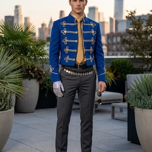 May include: A blue jacket with gold detailing and decorative buttons, worn with grey trousers and black boots. The outfit includes a gold tie and a silver glove. The background features a cityscape and potted plants.