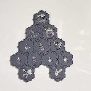 May include: A collection of gray hexagonal tiles featuring various cartoon character illustrations. Each tile has a unique design and a corresponding number. The tiles are arranged in a honeycomb pattern against a white background.