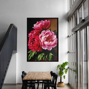 May include: A framed floral art print featuring a bouquet of vibrant pink peonies with green leaves against a dark background. The artwork is displayed in a modern interior setting, above a wooden table and black chairs.