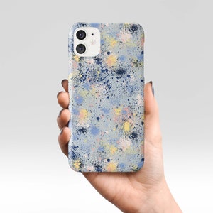 Puede incluir: Una funda para smartphone con un diseño de pintura salpicada colorida. La funda presenta un fondo azul claro con salpicaduras de pintura azul marino, amarilla, rosa y azul claro. La funda tiene un acabado brillante.
