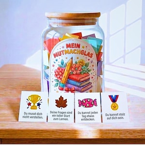 Puede incluir: Un frasco de vidrio transparente con tapa de madera lleno de notas de papel de colores. La etiqueta dice MEIN MUTMACHGLAS y muestra un lápiz, libros y flores. Hay cuatro tarjetas blancas delante con gráficos y texto en alemán.