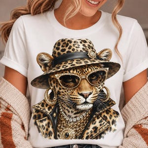 May include: A white t-shirt featuring a graphic print of a leopard wearing a leopard-print fedora, gold-rimmed sunglasses, large gold hoop earrings, a layered gold chain necklace, and a black leather-style jacket with gold accents.