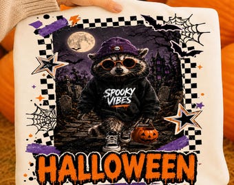Op de afbeelding: Een witte deken met een afbeelding van een wasbeer die een paarse muts, een oranje zonnebril en een zwarte hoodie met de tekst Spooky Vibes draagt. Het ontwerp bevat een kerkhof, een volle maan, vleermuizen, spinnenwebben en het woord Halloween.