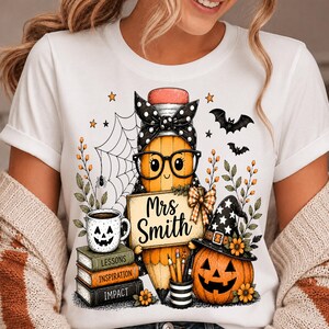 May include: A white t-shirt featuring a graphic of a yellow pencil character wearing black glasses and a polka-dot bow. The pencil holds a sign reading Mrs Smith, next to a stack of books labelled Lessons, Inspiration, Impact, and a jack-o'-lantern.