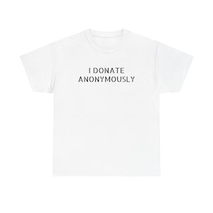 Puede incluir: Una camiseta blanca con el texto negro "I DONATE ANONYMOUSLY". La camiseta es de cuello redondo y manga corta. El texto está centrado en el pecho.