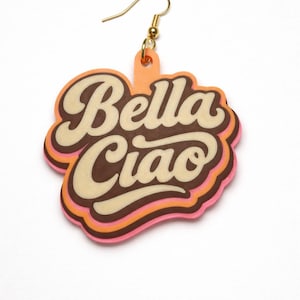 Op de afbeelding: Enkele oorbel met een goudkleurige haak. De oorbel heeft de vorm van een wolk met de woorden "Bella Ciao" in een retro lettertype. De tekst is in crème, bruin en oranje, met roze en bruine contouren.