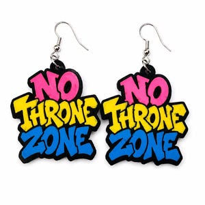 以下が含まれることがあります： 黒いベースにNO THRONE ZONEという文字が太いグラフィティスタイルで描かれたドロップイヤリングのペア。NOはピンク、THRONEは黄色、ZONEは青色です。各イヤリングは銀色の金属製フックから吊り下げられています。