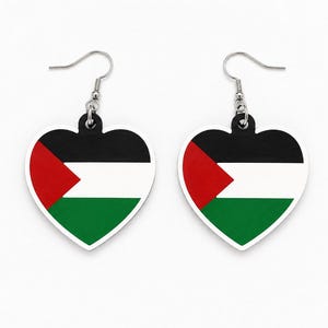 May include: A pair of heart-shaped drop earrings featuring the Palestinian flag design. Each earring displays a black horizontal stripe at the top, a white stripe in the middle, and a green stripe at the bottom, with a red triangle on the left side.